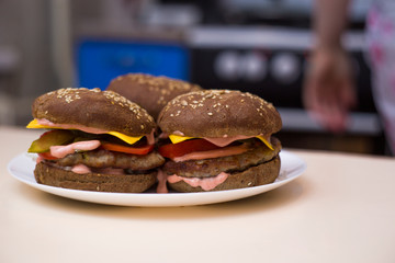 Classic hamburgers with bacon, meat, cheese, onions, tomatoes and cheese and a whole bun. On the plate. Close-up