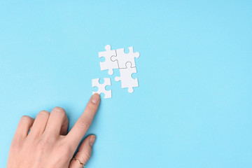 cropped shot of woman and white puzzles pieces on blue background