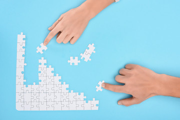 cropped shot of man and woman with white puzzle pieces on blue backdrop, cooperation concept