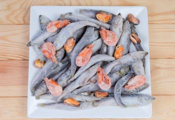 Top view of frozen various seafoods on square white dish