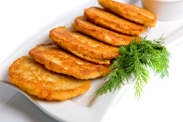 Pan-fried potato pancakes traditional potato fritters on a plate isolated on white background.