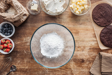 top view of bowl with flour and ingredients for sweet homemade cake on table
