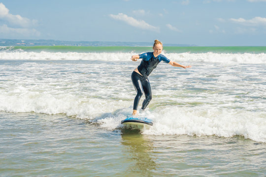 Joyful young woman beginner surfer with blue surf has fun on small sea waves. Active family lifestyle, people outdoor water sport lesson and swimming activity on surf camp summer vacation
