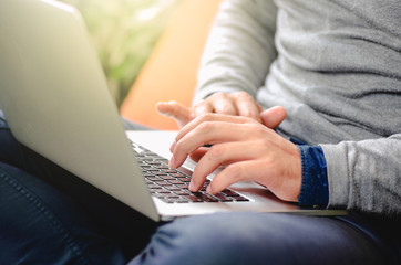 Close-up of man’s hands working on laptop in his lap