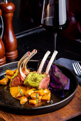delicious restaurant dish, rack of lamb in restaurant background. Healthy exclusive food on big black platter closeup