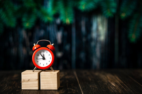 wooden cubesr with red alarm clock on dark blured background.