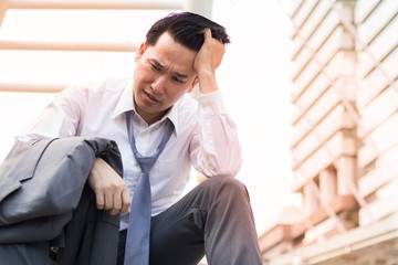 disappointed sad businessman with suit sitting at stair walk way in city after business project fail