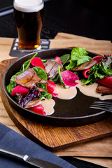delicious beef tongue with spinach and beetroot in restaurant background. Healthy exclusive food on big black platter closeup