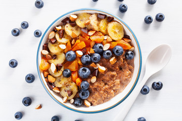 chocolate oatmeal porridge with blueberry, nuts, banana, dried apricot for healthy breakfast. Top...
