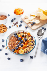 chocolate oatmeal porridge with blueberry, nuts, banana, dried apricot for healthy breakfast