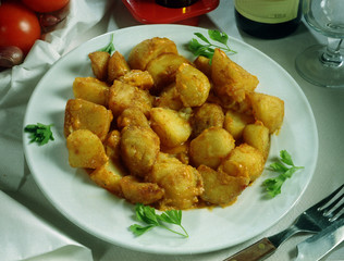 Plato de patatas fritas picantes adobadas con ajo y guindilla.
