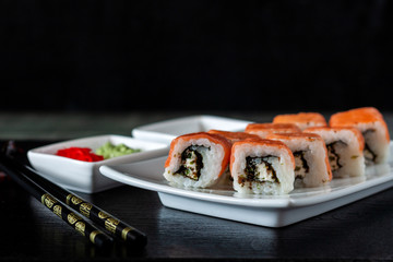 Traditional Japanese cuisine. Philadelphia sushi roll made of fresh salmon, avocado and cream cheese with black rice