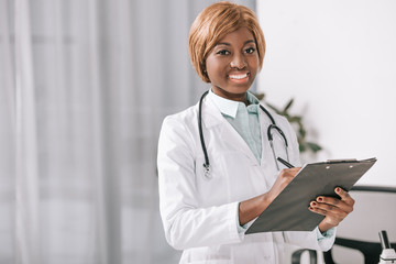 smiling african american doctor with stethoscope and clipboard