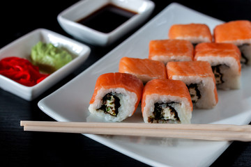 Traditional Japanese cuisine. Philadelphia sushi roll made of fresh salmon, avocado and cream cheese with black rice