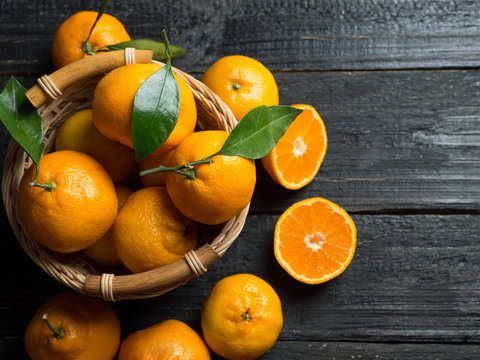 Ripe bright tangerines in a basket on a dark wooden background