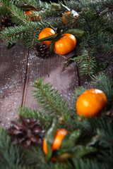 Tangerines with leaves and fir branches on a wooden background. Place an inscription or label. The concept of the holidays New year or Christmas.