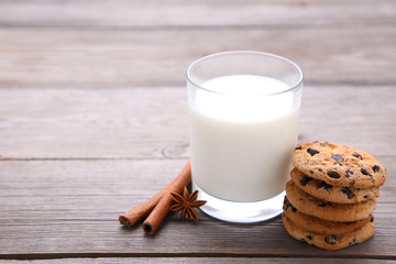 Glass of milk and chocolate cookies on grey background