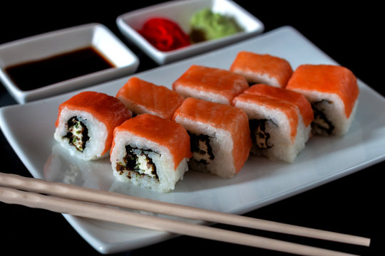 Traditional Japanese cuisine. Philadelphia sushi roll made of fresh salmon, avocado and cream cheese with black rice