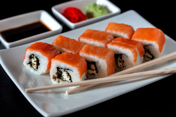 Traditional Japanese cuisine. Philadelphia sushi roll made of fresh salmon, avocado and cream cheese with black rice