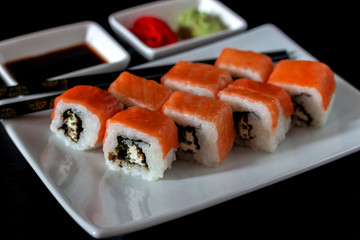 Traditional Japanese cuisine. Philadelphia sushi roll made of fresh salmon, avocado and cream cheese with black rice