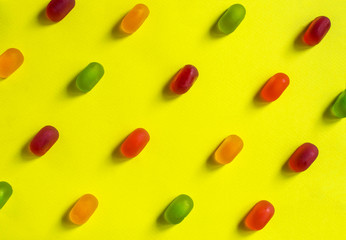 Multicolored jelly candy on a yellow background, top view