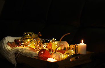 Various small pumpkins, leaves and berries and glowing lights. Dark photo. Halloween celebration. Holiday decorations.
