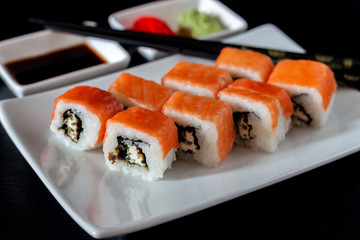 Traditional Japanese cuisine. Philadelphia sushi roll made of fresh salmon, avocado and cream cheese with black rice