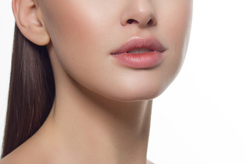 Obraz na płótnie Canvas Cosmetics, makeup and trends. Bright lip gloss and lipstick on lips. Closeup of beautiful female mouth with natural lip makeup. Beautiful part of female face. Perfect clean skin in natural light
