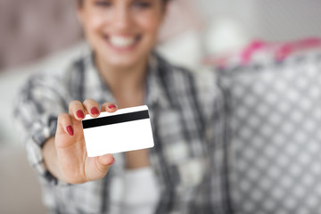 Young attractive woman shopping online at home. Beautiful lady at the bedroom with shopping bags. Girl holding a credit card indoors.