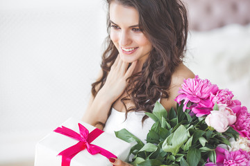 Young beautiful woman holding flowers. Attractive girl with peony pink. Beauty portrait. Female close up portrait