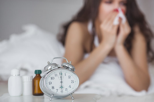 Sick woman lying in the bed. Girl taking medicine from the flu. Female got cold.