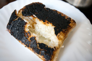 Completely burnt rice on plate next to pot standing on table in kitchen. Concept of unskilled, clumsy chef. Ruined dinner for family 