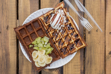 Belgian waffle with banana and kiwi and chocolate wafer with ice cream ball and chocolate topping.