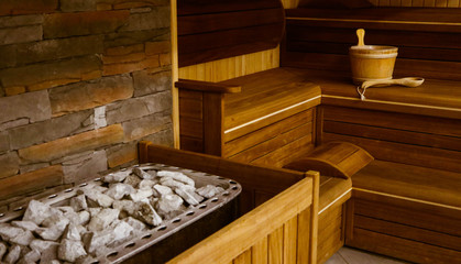 Wooden Bathhouse with a heating pot filled with stones, close up. Wooden sauna interior with...