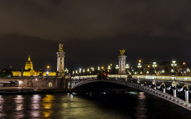 Obraz premium Pont Alexandre III on Seine River with Invalid dome in background at night - Paris France