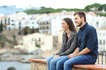 Couple or friends looking away on vacation in a coast town