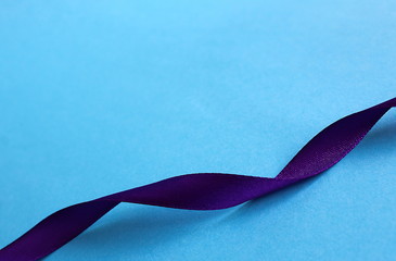Purple satin ribbon wriggles on blue background