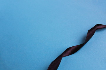 Black satin ribbon wriggles on blue background