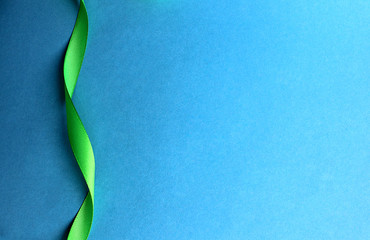 Green satin ribbon wriggles on blue background