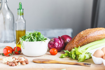 ingredients for salad, fresh vegetables, olive oil, nuts on the table in the kitchen. culinary and food concept