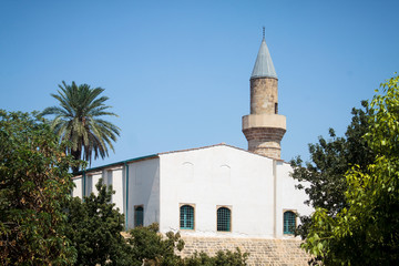 Religious white mosque with a minaret on a hill in one of the parks on the island of Cyprus