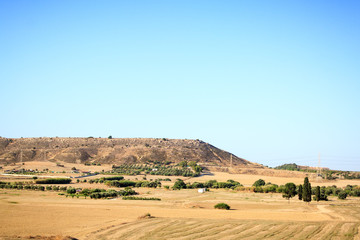 Fototapeta na wymiar View of the high sand hills and spacious farms, on which grow green olive trees and other plantations on the island of Cyprus