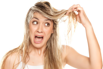 desperate blond woman with messy wet hair on white background