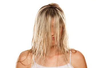 young blond woman with wet hair over her face on white background