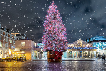 Naklejka premium Weihnachten in London: der beleuchtete Weihnachtsbaum im Bezirk Covent Garden bei Nacht mit Schneefall