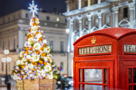 Rote Telefonzelle vor beleuchtetem Weihnachtsbaum in London zur Weihnachtszeit