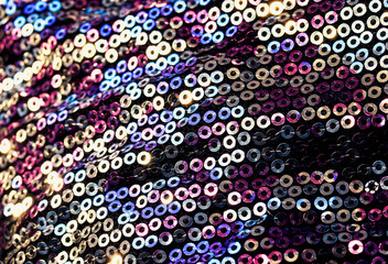 textured background of shiny round multicolored iridescent sequins sewn on fabric for a trendy evening dress
