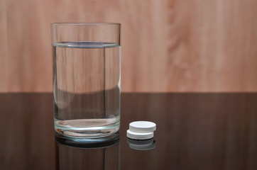 Anesthetic tablet, vitamins, in a glass of water with bubbles on a black table. Copy-space.