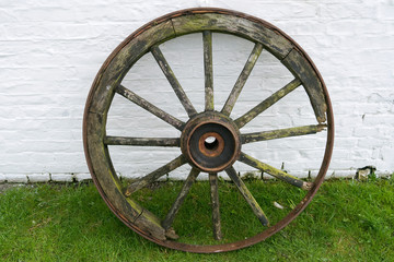 Laesoe / Denmark: Old wooden wheel leaning against the white painted brick wall of an ancient stable