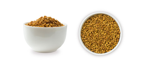 Fenugreek seeds in a wooden bowl isolated on white. Fenugreek seeds isolated on white background. Fenugreek with copy space for text.